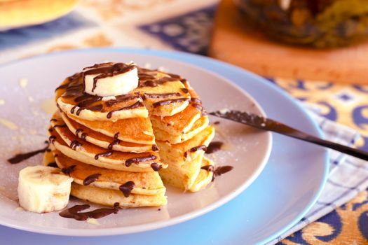 classic american breakfast. homemade banana pancakes on plate sprinkled powder and honey. A slide of hot pancakes with fresh bananas on a plate on the kitchen table . Pancake slide with honey topping