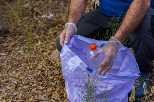 environmentalist man with garbage bags picking up garbage from the field and taking care of the environment