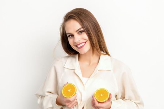 Young Caucasian smiling woman holding slices orange over isolated white background, breast health concept