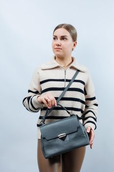 Woman with a gray leather bag on a white background. Stylish clutch bag. Close-up vertical photo.
