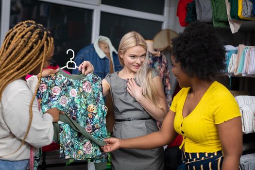 Two dark-skinned shopkeepers show a blouse to a new customer and tell her that this blouse is perfect just for her. A store and a tailor's store.