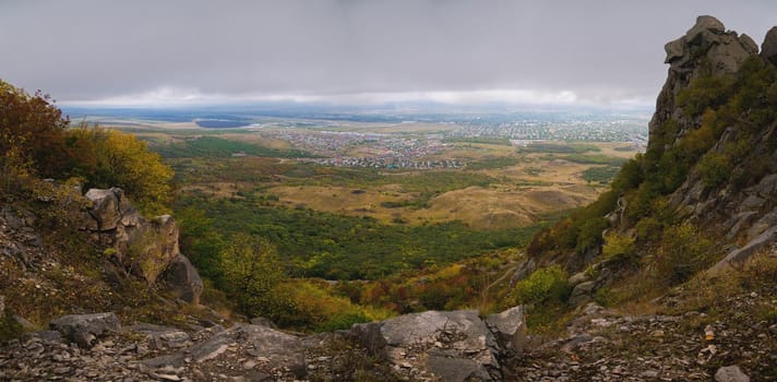 rocky cliff at the foot of the village against a cloudy sky, after or before a thunderstorm, panoramic view.