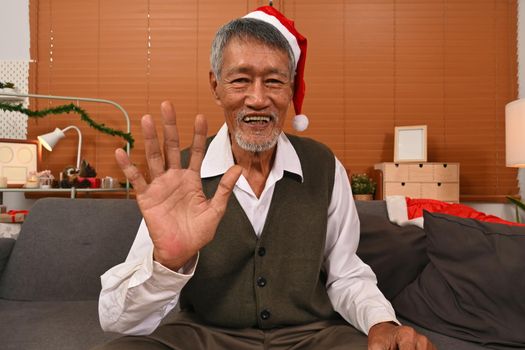 Head shot web camera view of happy mature man having a video call with friends or family on Christmas holidays.