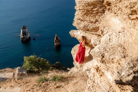 A woman in a red flying dress fluttering in the wind, against the backdrop of the sea