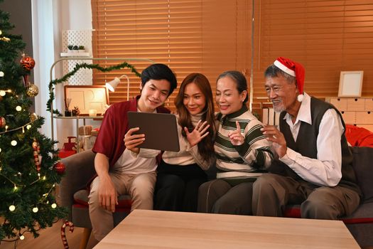 Joyful family having a video call on digital tablet, congratulating relatives during Christmas or New year holidays.