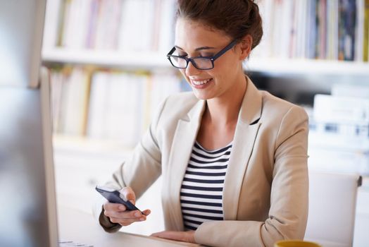 Communication for the connected. an attractive young woman looking at her phone while working from home