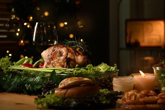 Roasted turkey on Thanksgiving table or Christmas dinner by candlelight in a decorated room with a Christmas tree.