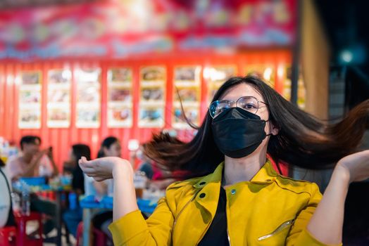 Beautiful asian woman (LGBTQ) natural makeup wear fashion yellow leather clothes with glasses posing with food or drink at thai street food, market or restaurant outdoor fashion style