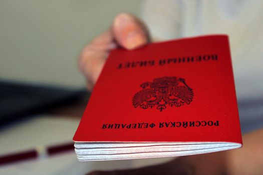 The girl holds out a military ID issued by the Russian Federation. Close-up. Blurred background. The concept of mobilization.