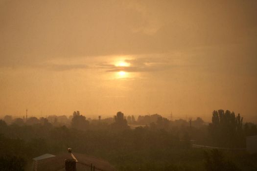 Sunset against dirty rain. Brown color atmosphere.