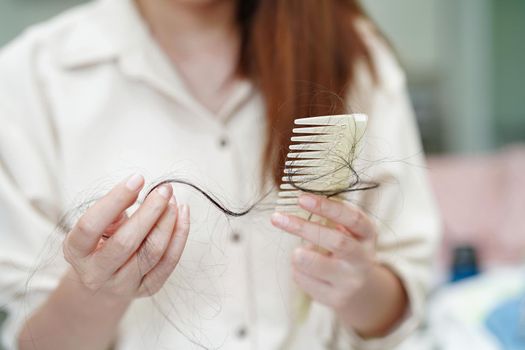 Asian woman have problem with long hair loss attach in her hand.