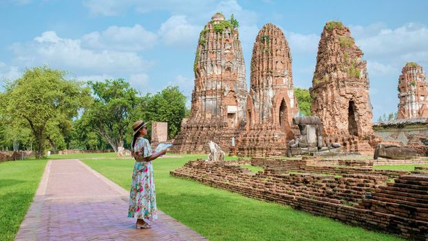 Ayutthaya, Thailand at Wat Mahathat, women with a hat and tourist maps visiting Ayyuthaya Thailand. Tourist with map in Thailand