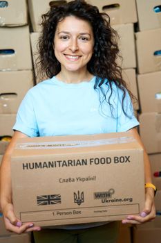 Portrait of Ukrainian volunteer woman with paper box of humanitarian aid. Dnipro, Ukraine - 06.30.2022