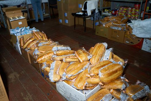 Humanitarian aid warehouse in ukrainian volunteer centre, boxes with bread. Dnipro, Ukraine - 06.30.2022