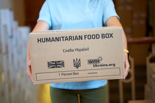 Portrait of Ukrainian volunteer woman with paper box of humanitarian aid. Dnipro, Ukraine - 06.30.2022