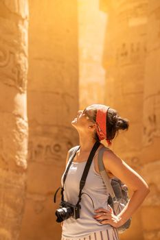 Tourist looking up to columns with hieroglyphs in a temple in Karnak in Egypt