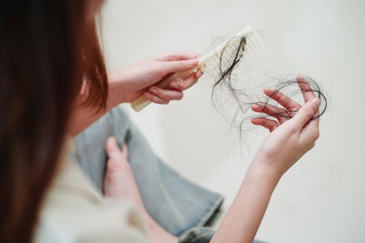 Asian woman have problem with long hair loss attach to comb brush.
