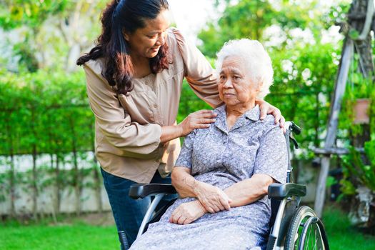 Caregiver help Asian elderly woman disability patient sitting on wheelchair in park, medical concept.