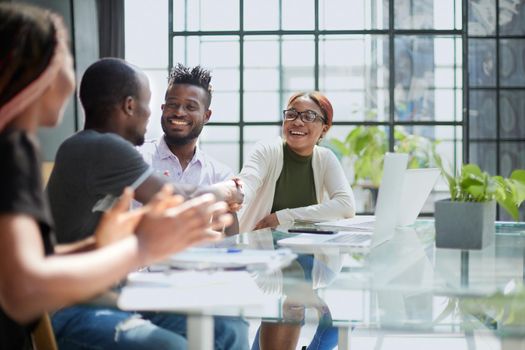 team of young african people in the office shaking hands