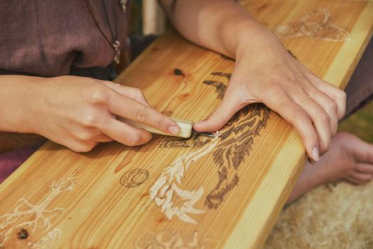 Hojbjerg, Denmark, August, 2022: Retro photo. Girl carving wood at the viking festival