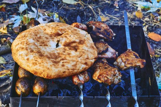 flat hollow unleavened bread that can be split open to hold a filling. East caucasian bread lavash pita and meat on a grill grate on a fire. High quality photo