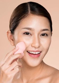 Closeup ardent woman applying her cheek with dry powder and looking at camera. Portrait of younger with perfect makeup and healthy skin concept.