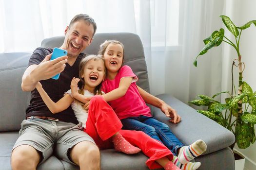 Smile! Young father and his little daughter taking selfie while sitting at home