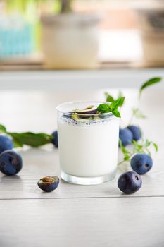 sweet homemade yogurt with fresh plum slices in a glass on a wooden table