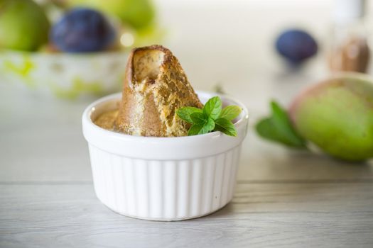 pear baked in curd dough in a small ceramic form, on a wooden table.