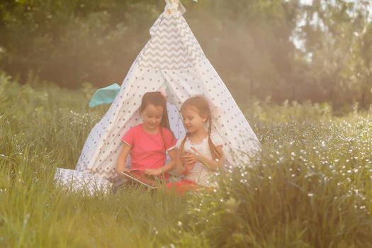 two little girls play near wigwam tent