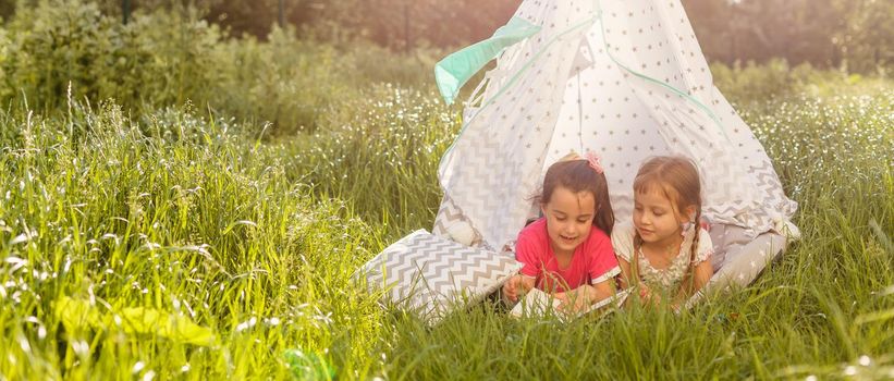 Two little girls are playing in a tent in the park