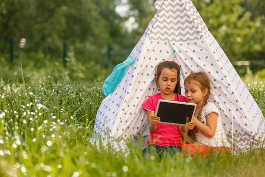 children playing in tablet pc in a tent