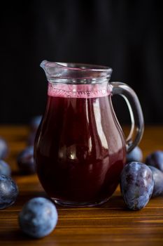 sweet plum syrup in a glass decanter on a wooden table