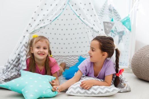 Two cute happy girls play at home. Funny lovely sisters are having fun in children room. Girls play