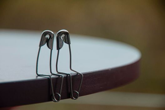 Safety pin couple sitting on table with customizable space for text and ideas. Love and romance concept.