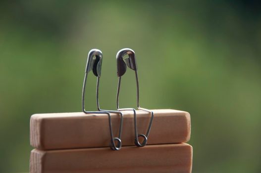 Safety pin couple sitting on wooden blocks with customizable space for text and ideas. Copy space and romance concept.