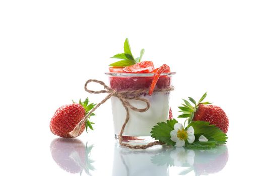 sweet homemade yogurt with strawberry jam and fresh strawberries in a glass, isolated on white background.