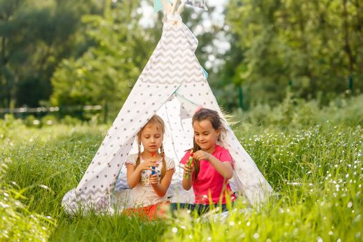 Two little girls are playing in a tent in the park