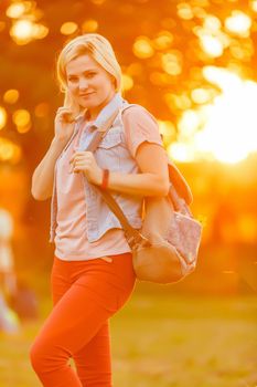 Student girl outside in summer park smiling happy. female college or university student.Caucasian young woman model wearing school bag