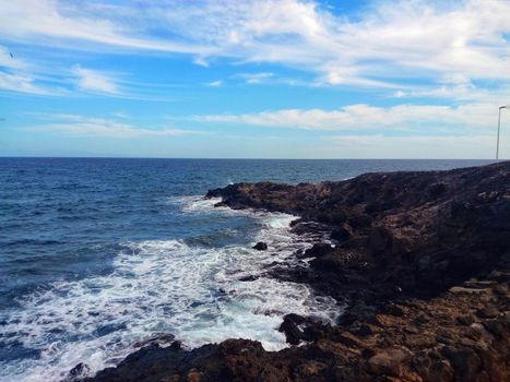 Rocky coast. Sea coast with rocks and splashing waves. Seascape with a cliff on a summer day. Beautiful pristine nature