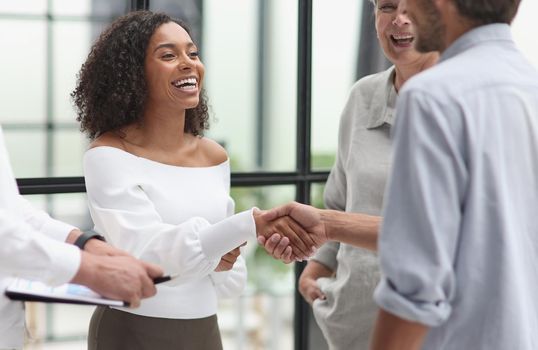 Smiling multiethnic businesspeople shaking hand in office.