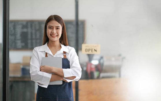 Startup successful small business owner sme beauty girl stand with tablet smartphone in coffee shop restaurant. Portrait of asian tan woman barista cafe owner. SME entrepreneur seller business concept.