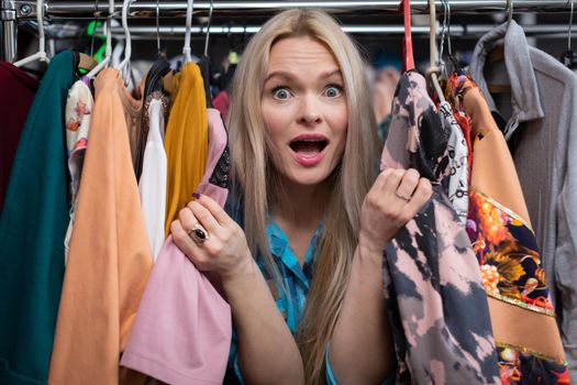 A happy woman shopping. The backstory of a clothing store. A thrilling and exciting shopping experience for every woman. . Blonde woman with straight long hair.