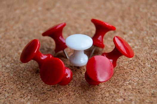 White push pin surrounded by red push pins. Harassment and discrimination concept.
