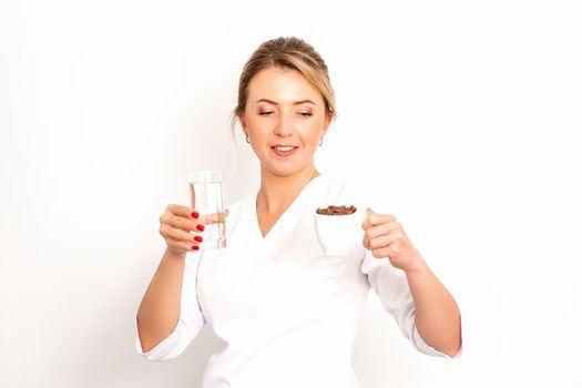 Coffee with water. The female nutritionist holds a cup of coffee beans and a glass of water in her hands on white background