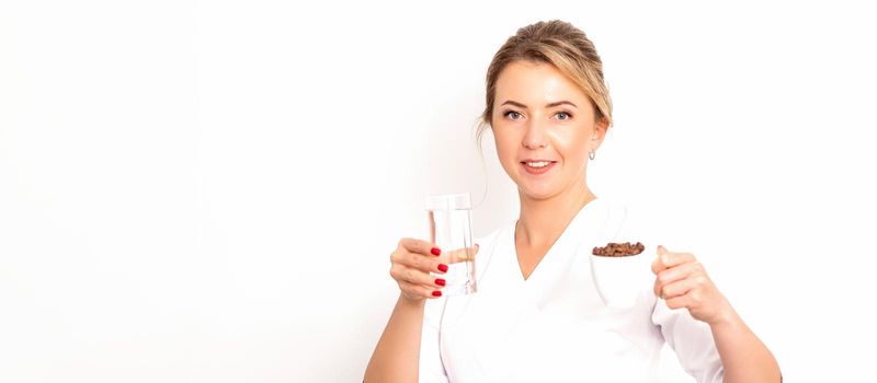 Coffee with water. The female nutritionist holds a cup of coffee beans and a glass of water in her hands on white background