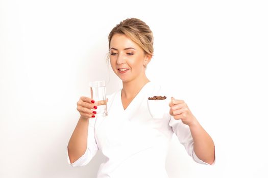 Coffee with water. The female nutritionist holds a cup of coffee beans and a glass of water in her hands on white background