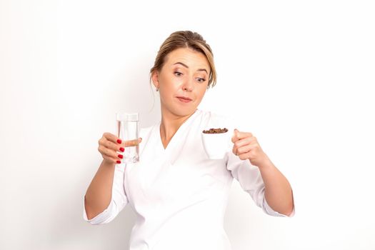 Coffee with water. The female nutritionist holds a cup of coffee beans and a glass of water in her hands on white background