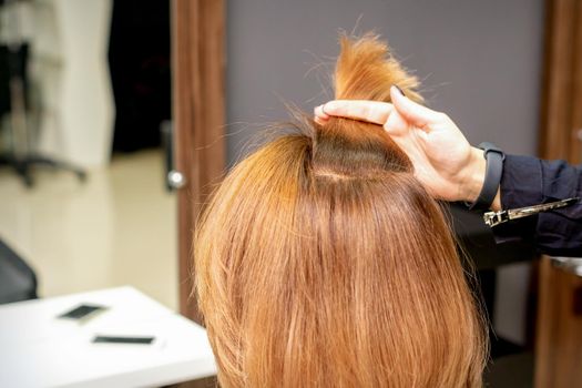 The hairdresser holds a strand in hand between fingers of the female hair. Examination of the hair of the young woman in a hairdressing salon