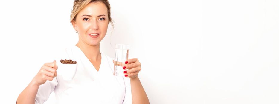 Coffee with water. The female nutritionist holds a cup of coffee beans and a glass of water in her hands on white background